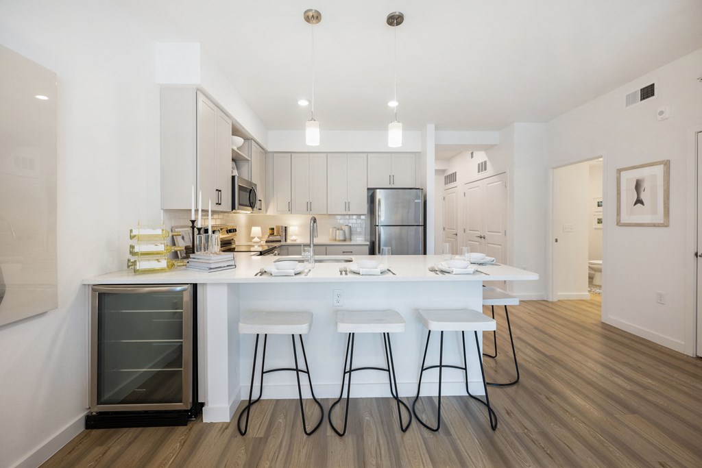 a kitchen with white cabinets and a large white island with three white stools