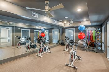 a gym with exercise bikes and other equipment at the enclave at woodbridge apartments in sugar land