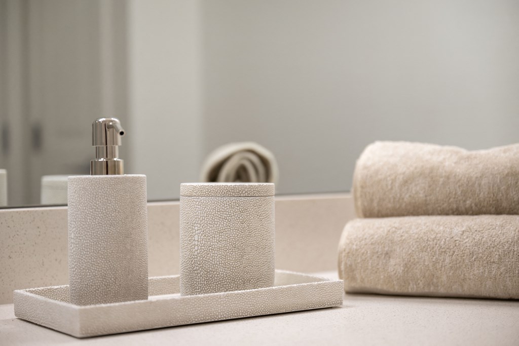 a bathroom sink with a soap dispenser and towels in the background
