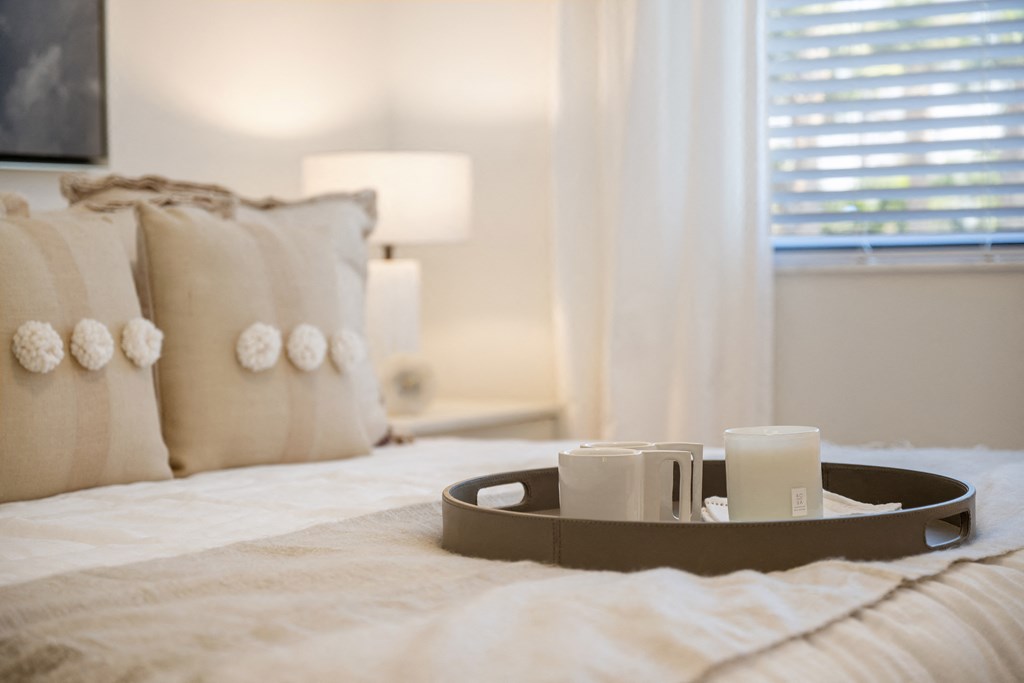 a bedroom with a tray of candles on the bed and a window in the background