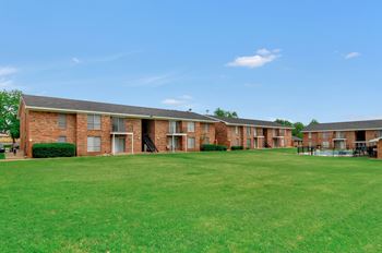A large grassy field in front of a brick building.