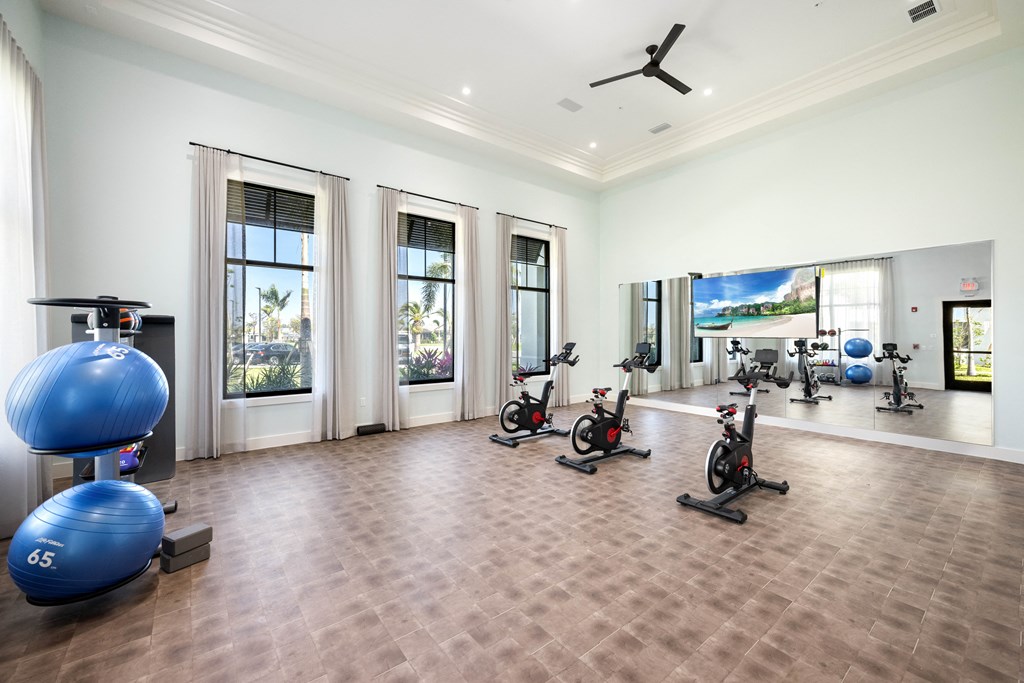 a workout room with exercise bikes and a large screen on the wall