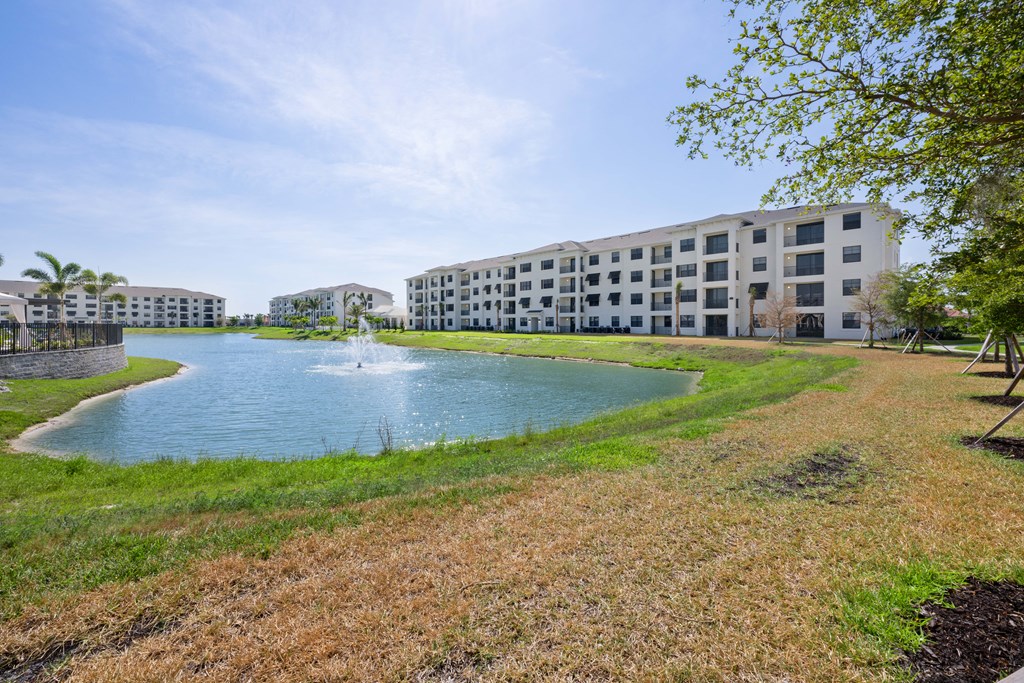 a grassy area with a fountain and apartment buildings in the background