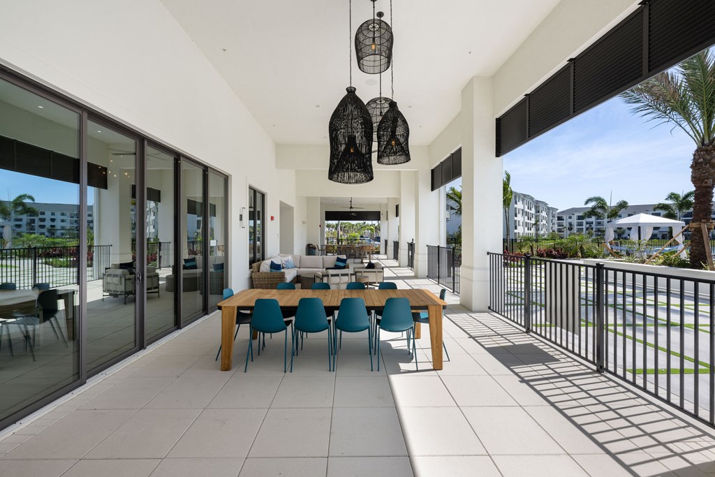 a large patio with a long wooden table and blue chairs
