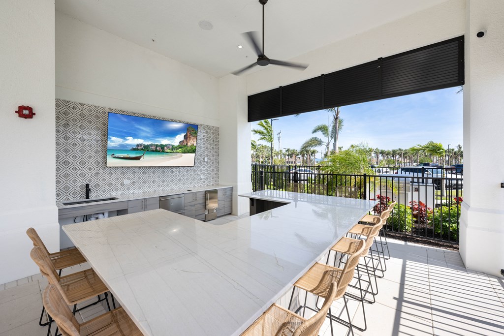 a kitchen and dining area with a large white table and chairs and a flat screen tv on