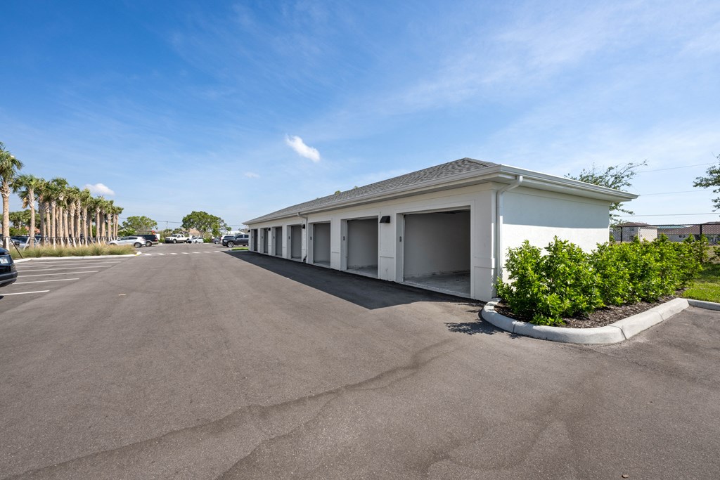 a white building with a garage and a parking lot in front of it
