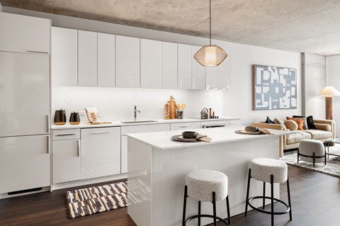 A modern kitchen with white cabinets and a white island with two stools.