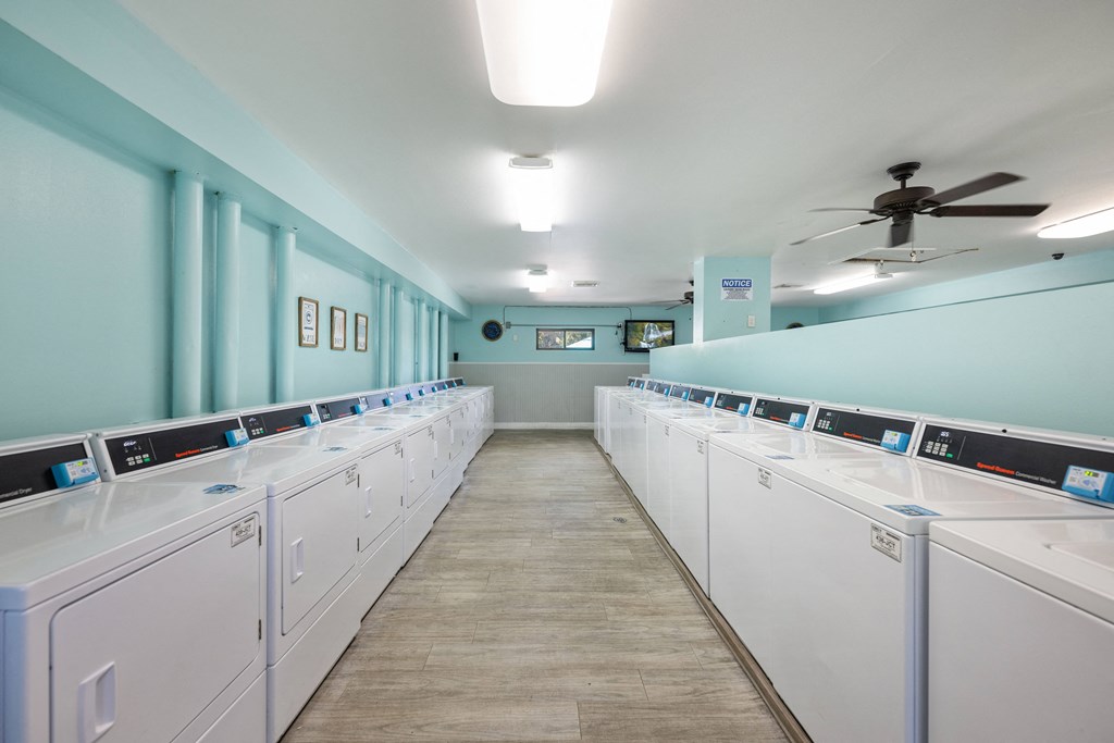 a laundry room with white washers and dryers and blue walls