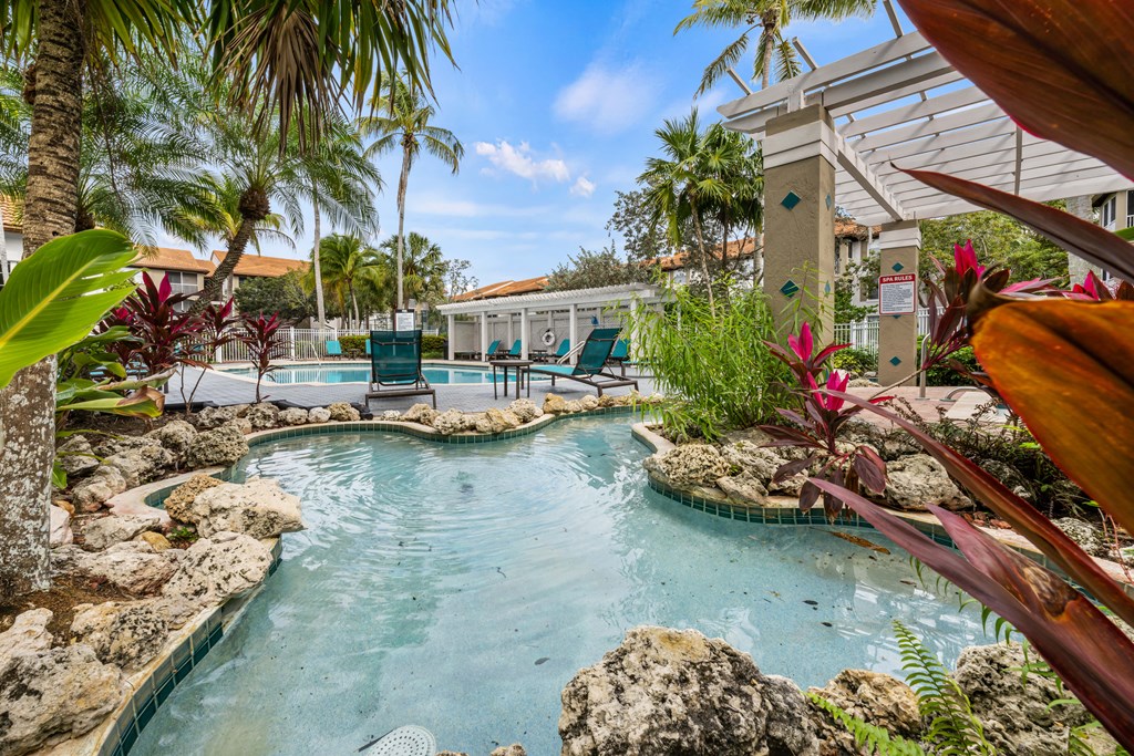 a resort style swimming pool with rocks and palm trees