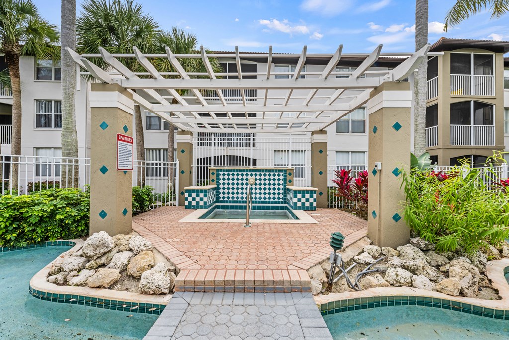a patio with a pool and a swing bench in front of an apartment building