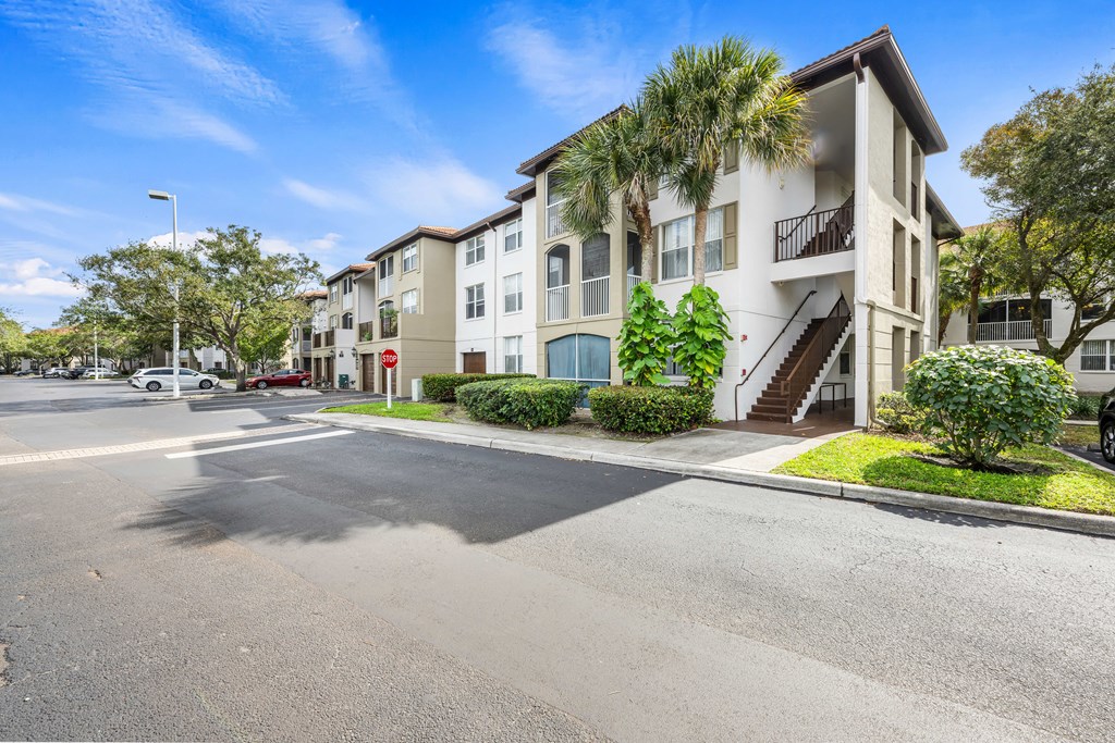 an empty street in front of an apartment building with palm trees