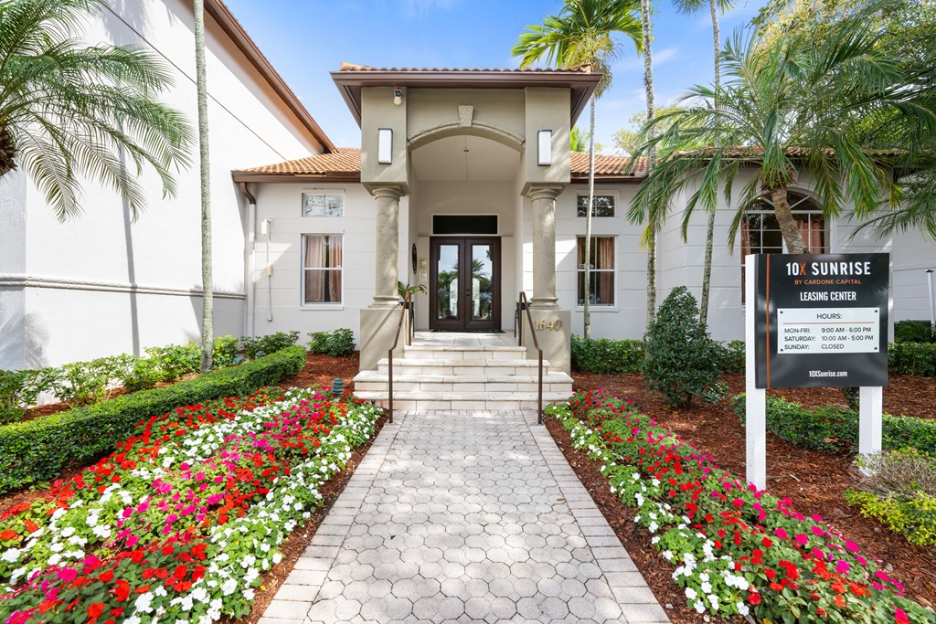 a building with a sign and flowers in front of it