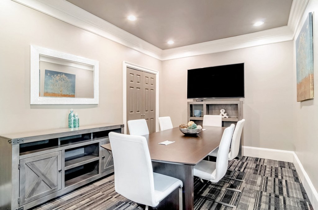 a dining room with a table and chairs and a tv on the wall