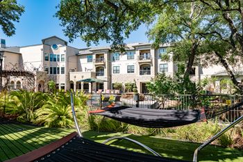 A hammock is suspended between two trees in a backyard.
