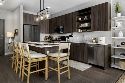 A modern kitchen with wooden chairs and a central island.