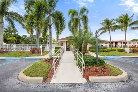 A building is surrounded by palm trees and a small garden.