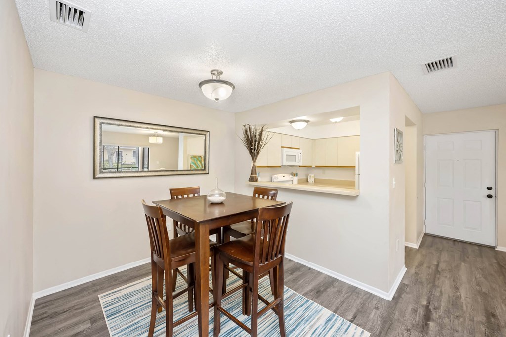 a dining area with a table and chairs and a kitchen in the background