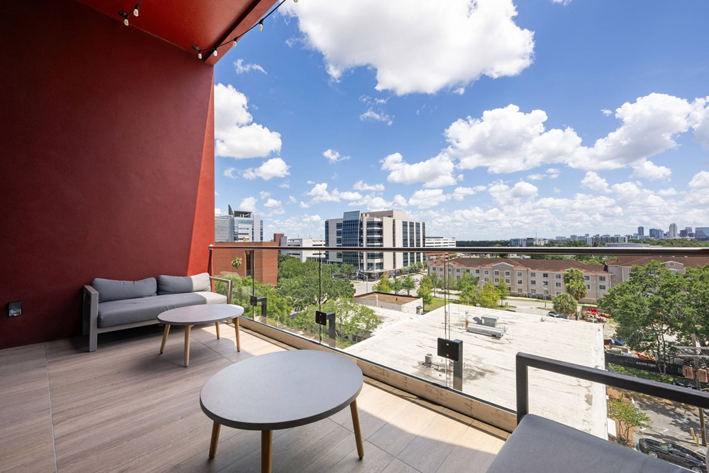 a view of the city from a balcony with couches and tables