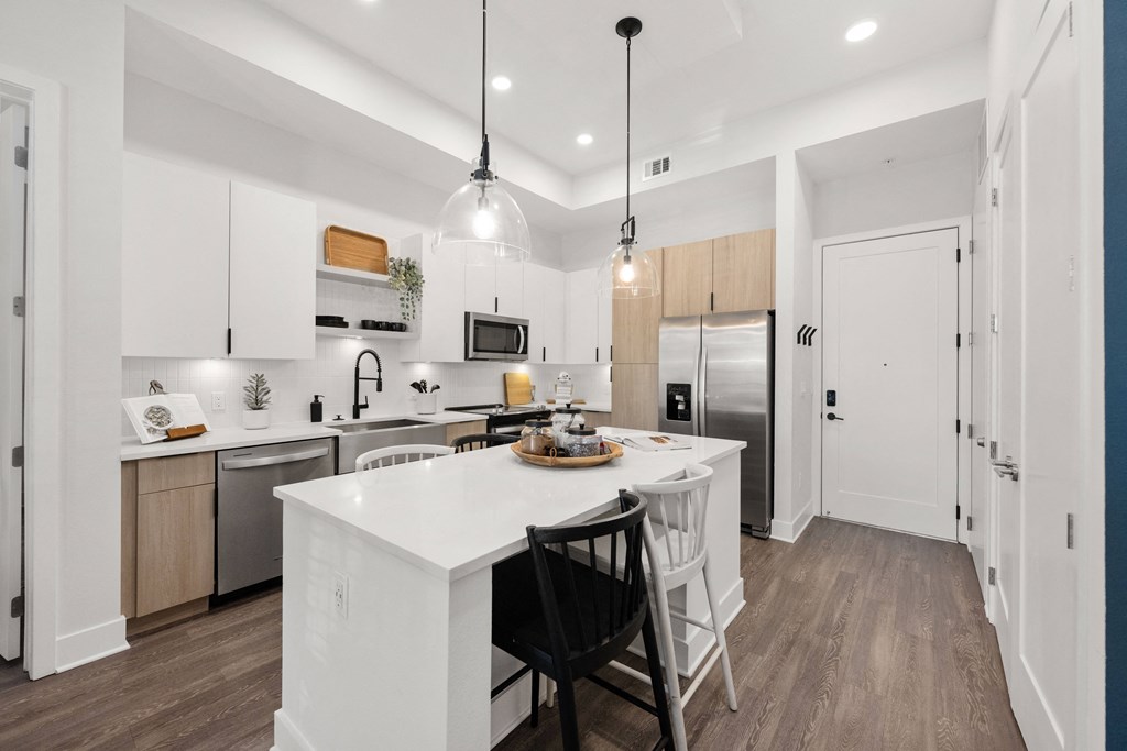an open kitchen with a large white island with two black chairs