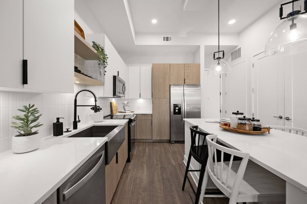 a modern kitchen with white counter tops and a large island with stools
