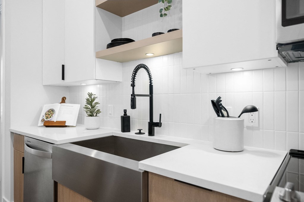 a kitchen with white counter tops and a black sink