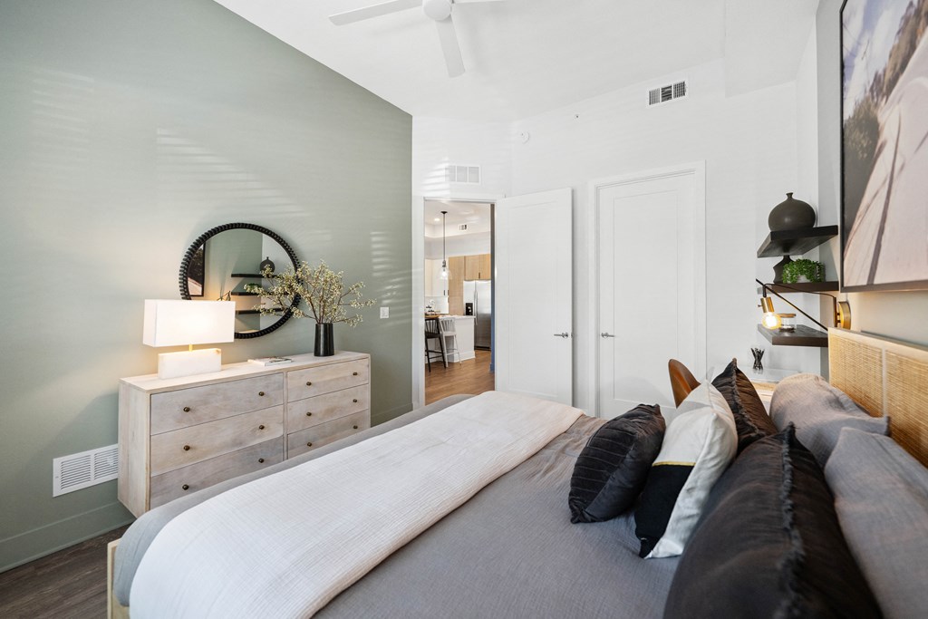 a bedroom with a large bed and a dresser with a mirror