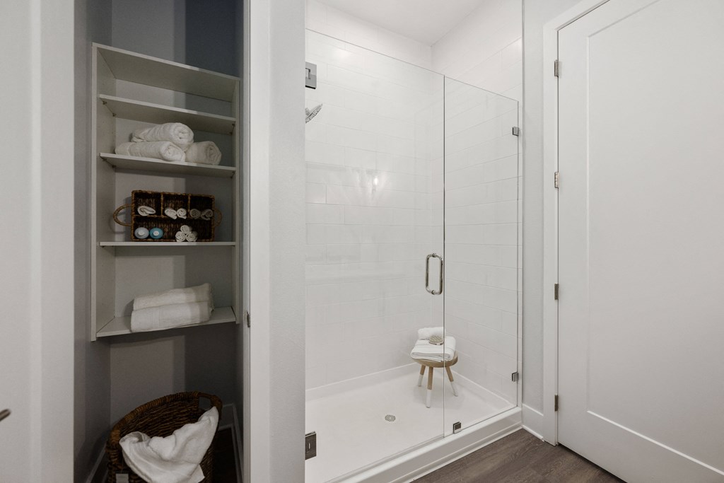 a white bathroom with a shower and shelves in it