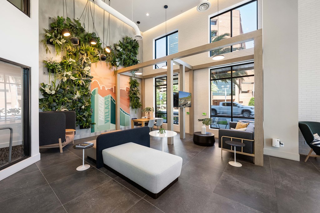 a lobby with couches and chairs and a wall of plants