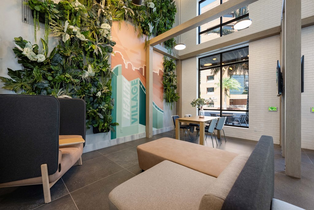 a living room with couches and a table and a wall of plants