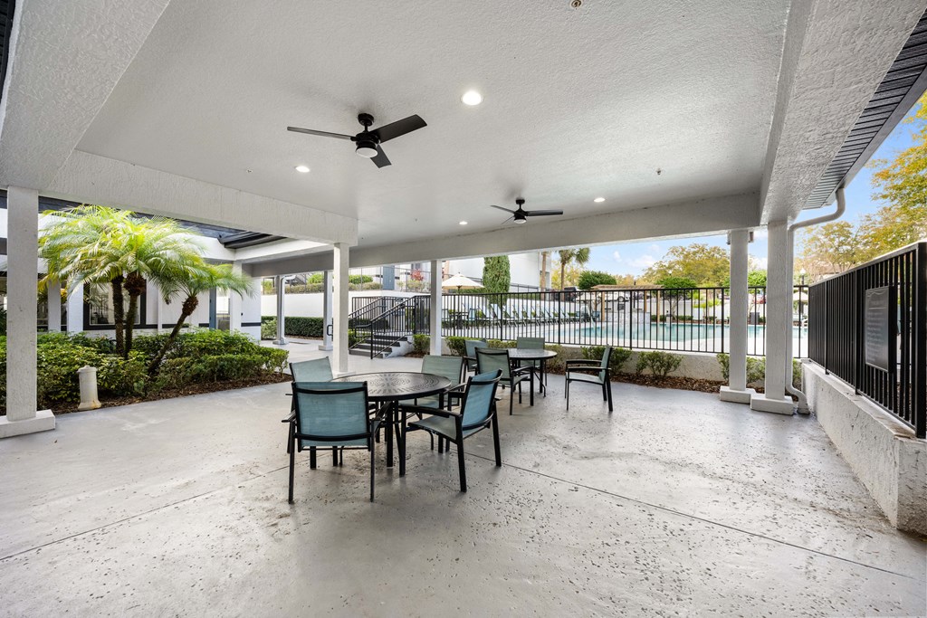 a patio with a table and chairs and a ceiling fan