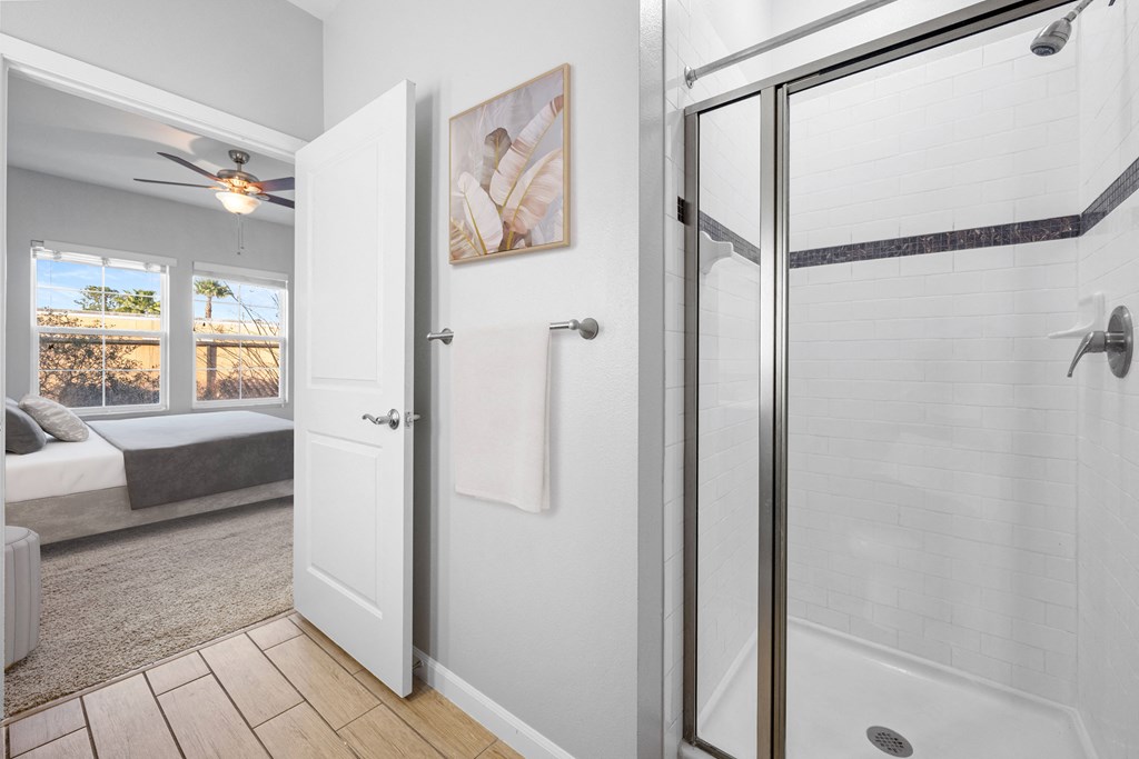 a white bathroom with a shower and a bed in the corner