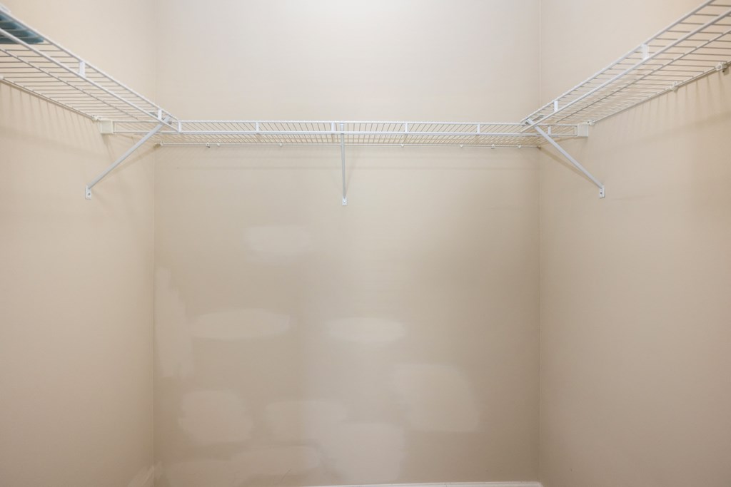 an empty closet in a room with white walls and a wire rack on the ceiling