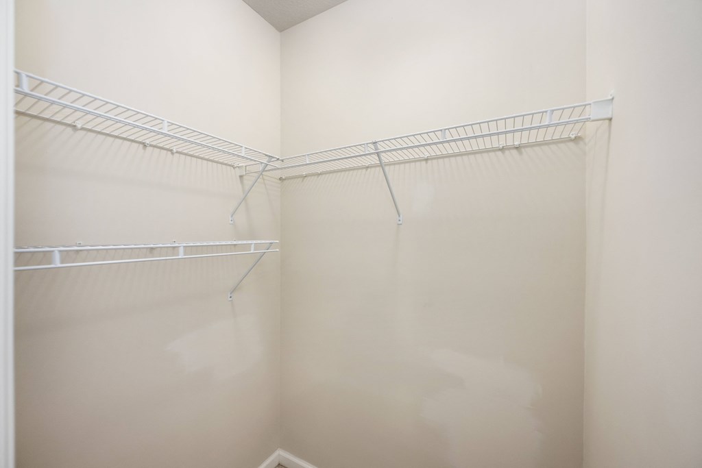 a walk in closet with empty shelves in a white room
