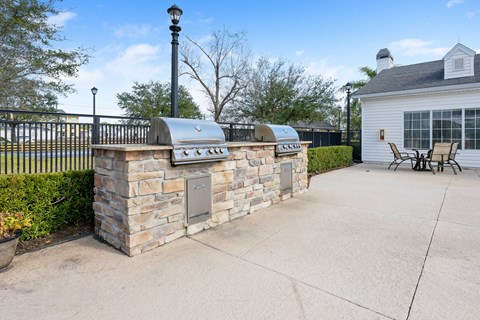 a stone outdoor kitchen with a grill and a table and chairs
