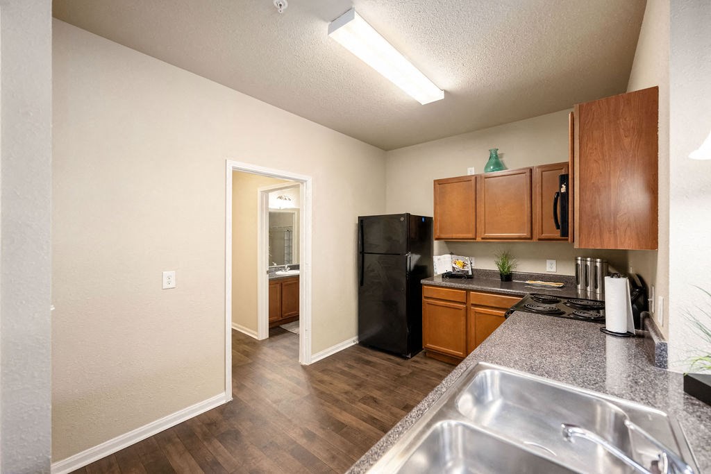 A kitchen with a black refrigerator and wooden cabinets.
