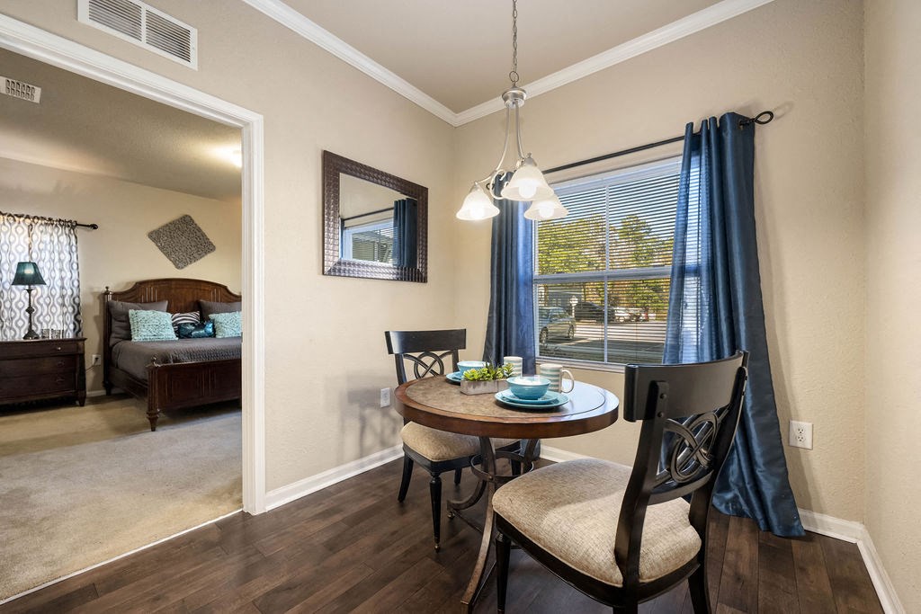 A dining room with a table set for two and a view of the backyard.