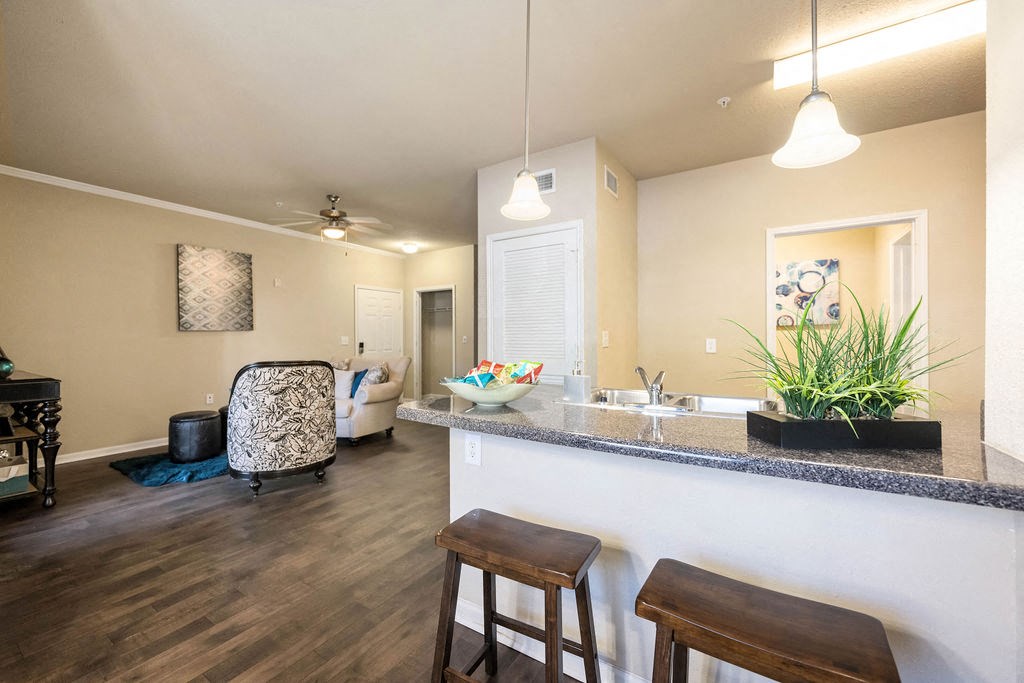 A kitchen with a bar stool and a chair with a patterned cushion.
