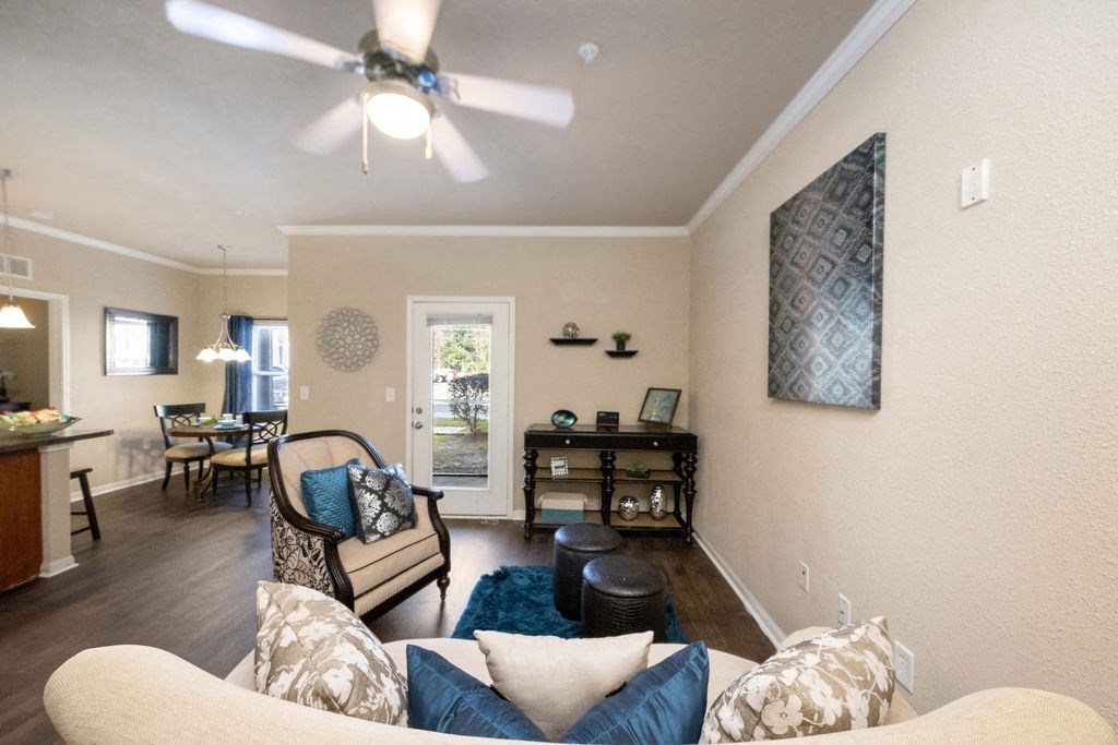 A living room with a white ceiling fan and a white couch with blue and white pillows.