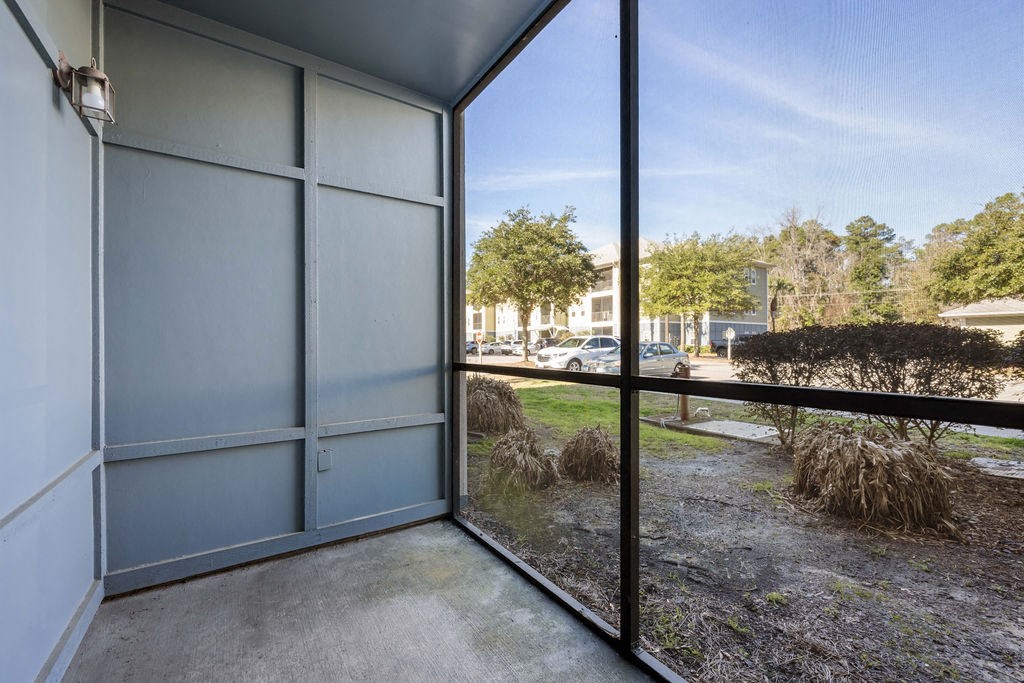 A view from inside a building looking out to a parking lot and trees.