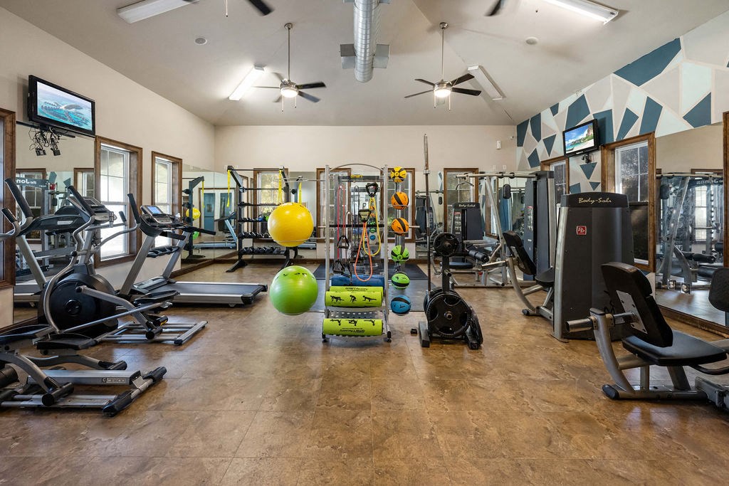 A gym with a variety of equipment including treadmills, weights, and a television.