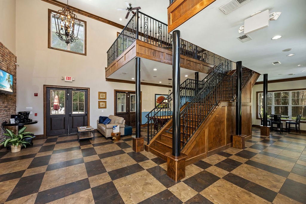 A large room with a checkered floor and a staircase with a metal railing.