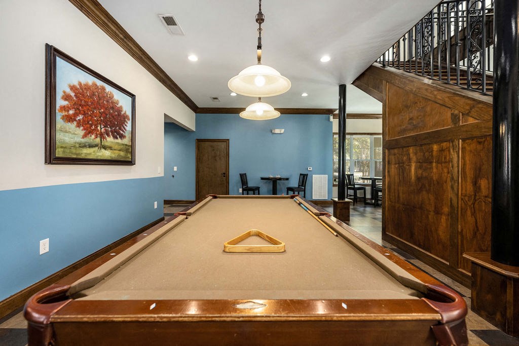 A pool table in a room with a blue wall and a painting of a tree.