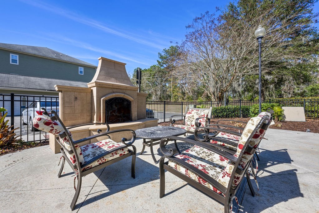 A patio with a fireplace, chairs and a table.