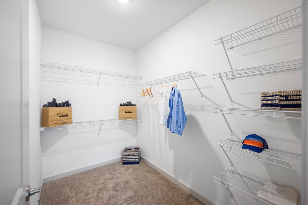 a walk in closet with white walls and shelves and two wire racks on the wall