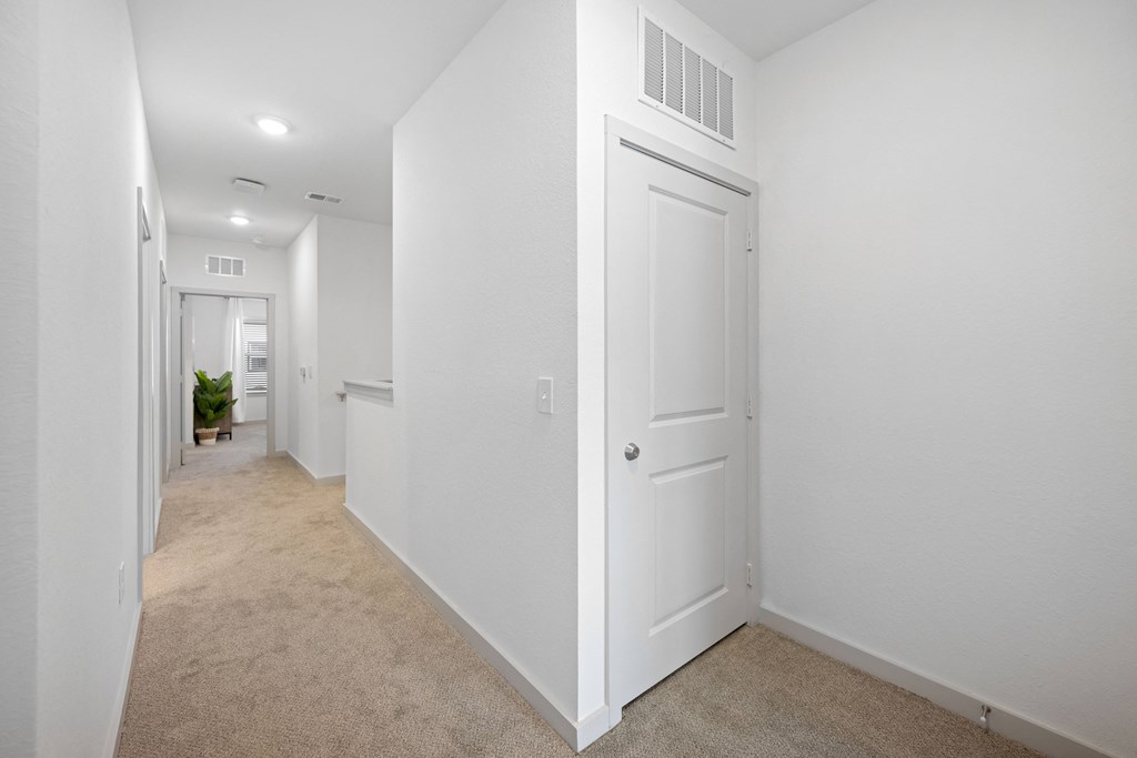 a corridor with white walls and white doors and a carpeted floor