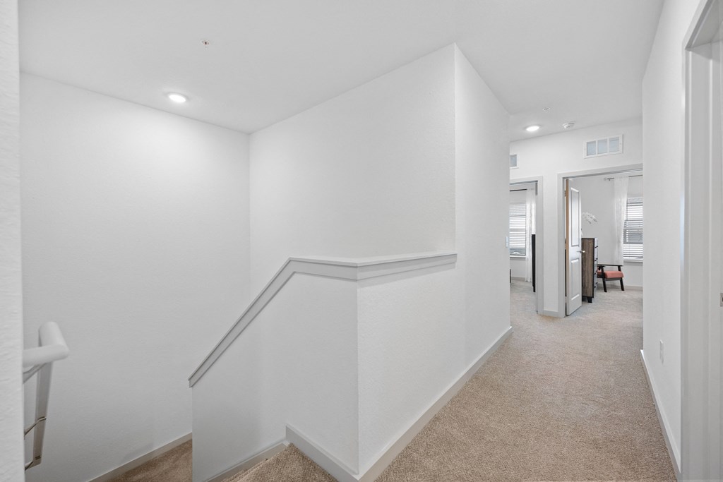 a renovated living room and hallway with white walls and white stairs