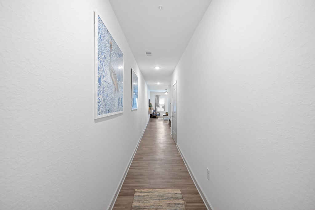 a long hallway with white walls and wooden floors and paintings on the wall