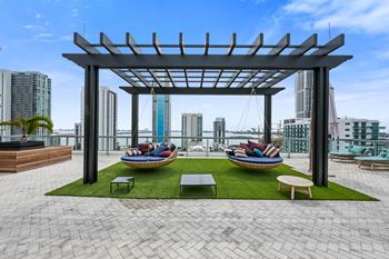 an outdoor area with lounge chairs and a hammock with a view of the city