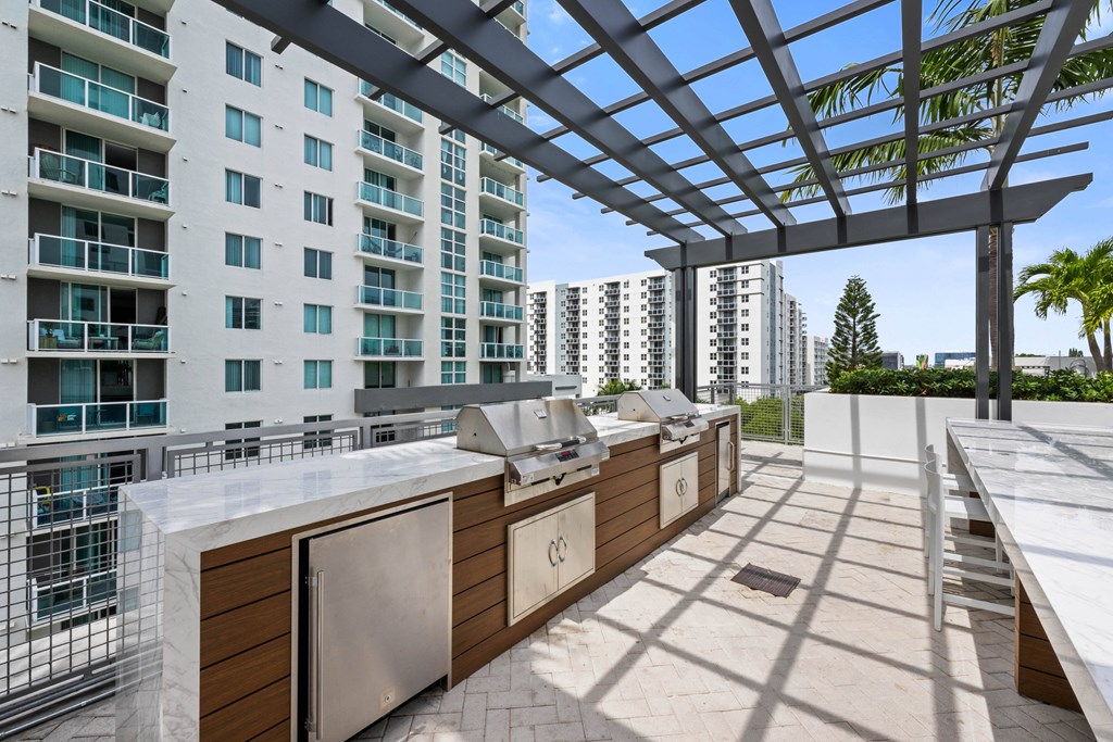 an outdoor kitchen with two bbq pits and a pergola