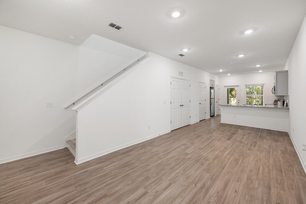 A spacious room with wooden flooring and white walls.